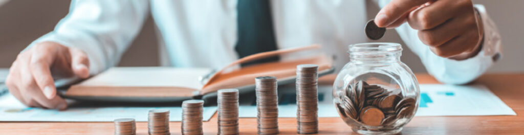 Stacks of coins increasing in height with man placing coin in jar representing savings on telecom spend.