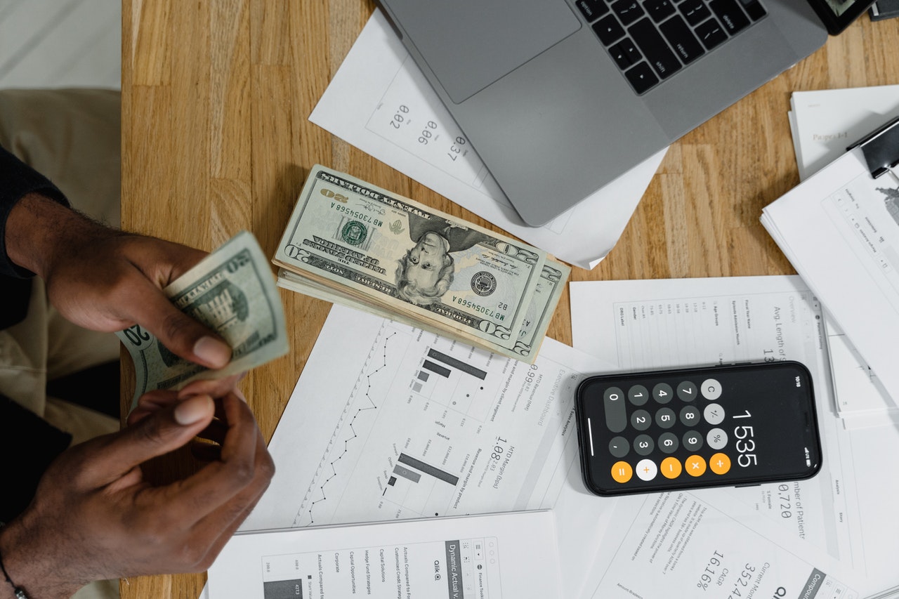 Desk with money, calculator and spreadsheets showing how UTR audits your telecom invoices to find and correct billing errors.